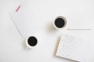 birds eye view of two white coffee mugs and journals