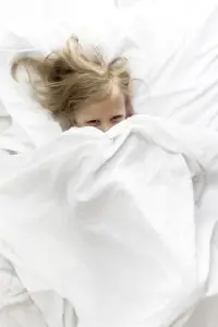 child in lying in bed smiling 