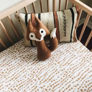wood crib with stripe pillow and plush brown fox