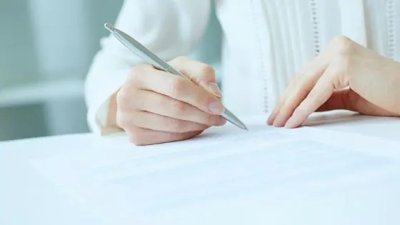 white woman signing a paper 